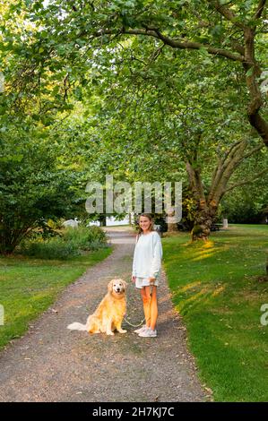 Mädchen und ihr Hund posieren auf einem Pfad in einem Stadtpark Stockfoto