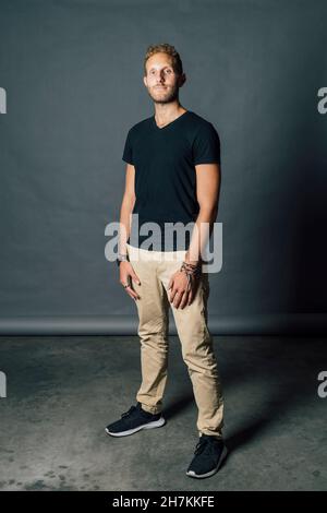 Junger Mann, der vor grauem Hintergrund steht Stockfoto