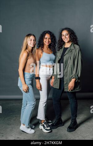 Junge Frauen stehen vor grauem Hintergrund Stockfoto