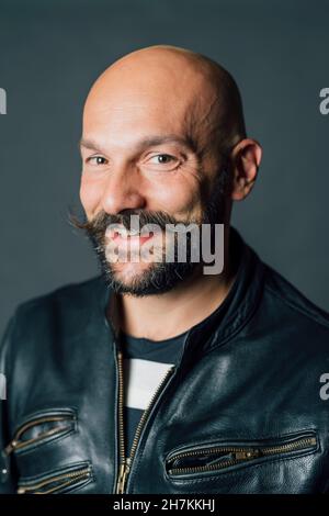 Lächelnder Mann mit Bart und Schnurrbart vor grauem Hintergrund Stockfoto