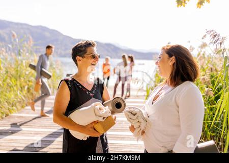 Frau mit Sonnenbrille im Gespräch mit einer Freundin beim Yoga-Kurs Stockfoto