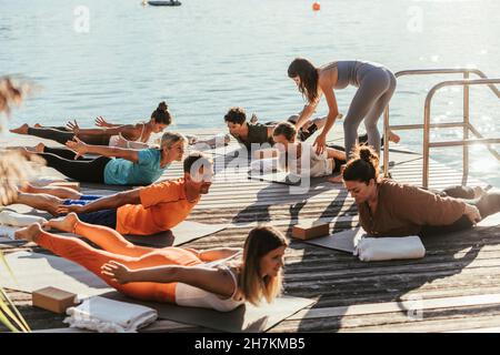 Weibliche Ausbilderin führt Frau beim Yoga während des Unterrichts Stockfoto