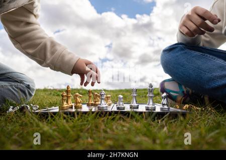 Schwestern spielen Schach, während sie auf dem Gras sitzen Stockfoto