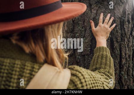 Frau berührt Baumrinde im Wald Stockfoto