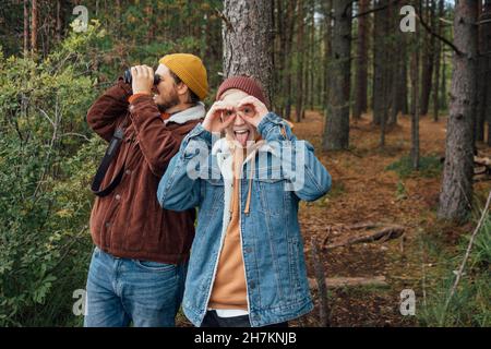 Junge ragt aus der Zunge, während er beim Vater Vogel im Wald beobachtet Stockfoto