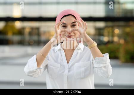 Junge Frau mit Kopftuch und Händen hinter dem Kopf Stockfoto