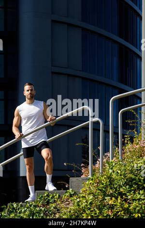 Junger Athlet, der an sonnigen Tagen am Geländer steht Stockfoto