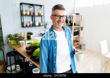 Mann mit der Hand in der Tasche hält die Kaffeetasse zu Hause Stockfoto
