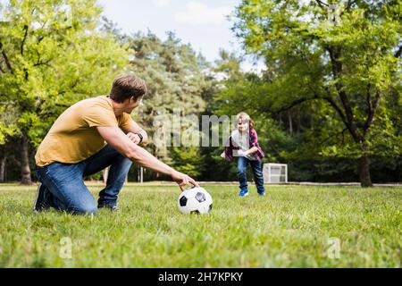 Mann und Junge spielen mit Fußball auf Gras Stockfoto