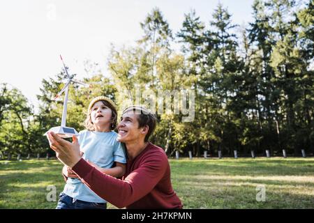 Vater hält Windturbinenmodell mit Sohn im Park Stockfoto