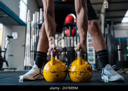 Muskulöser männlicher Athlet mit Kettlebells im Fitnessstudio Stockfoto