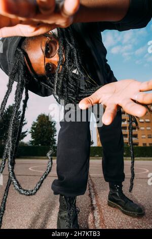 Frau mit Sonnenbrille, die sich am Sportplatz beugt Stockfoto