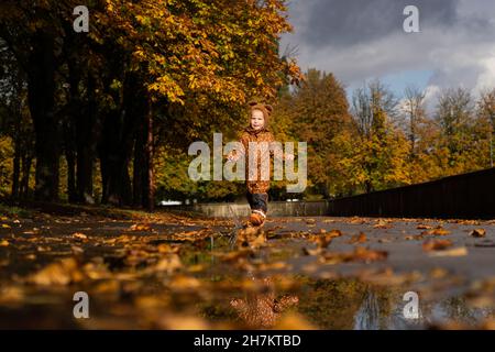 Mädchen mit braunem Regenmantel zu Fuß im Herbstpark Stockfoto