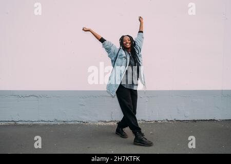 Glückliche Frau mit erhobenen Händen tanzt auf dem Fußweg Stockfoto