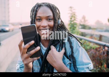 Lächelnde Frau, die während des Sonnenuntergangs das Mobiltelefon hält Stockfoto