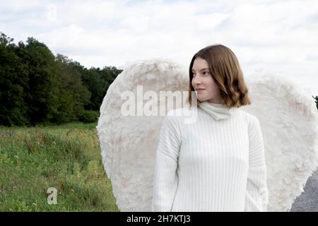 Lächelndes Teenager-Mädchen mit weißen Flügeln Stockfoto