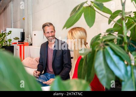 Lächelnder Geschäftsmann, der mit einem Kollegen im Büro zusammenarbeitet Stockfoto