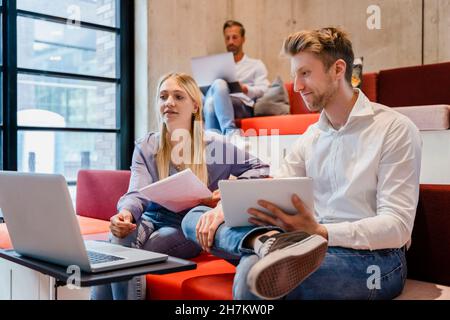 Junge Kollegen mit Laptop am Schreibtisch Stockfoto