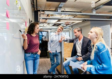 Geschäftsfrau, die Kollegen am Whiteboard vorführt Stockfoto