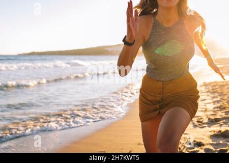 Frau, die am Strand am Ufer läuft Stockfoto