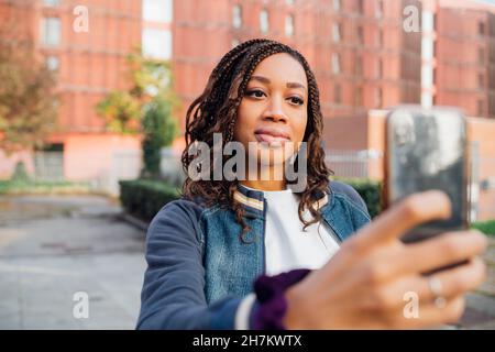 Frau mit geflochtenen Haaren, die Selfie über das Mobiltelefon nimmt Stockfoto