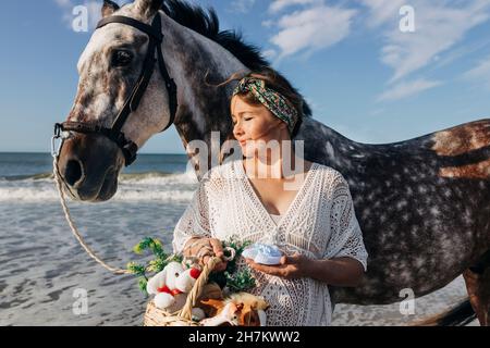 Eine Schwangerin mit einem Pferdekorb und Babybooties am Strand Stockfoto