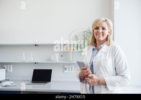 Blonde Wissenschaftlerin hält Tablet-PC im Labor Stockfoto