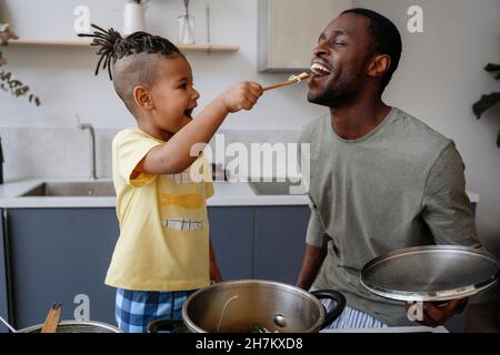 Junge füttert Spaghetti an den Vater in der Küche Stockfoto