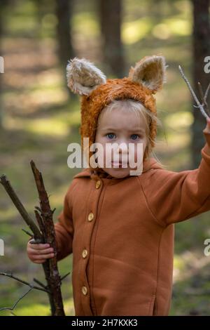 Nettes Mädchen mit Holzstäben, die Zunge im Wald hervorstechen Stockfoto