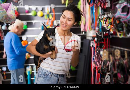 Asiatische Frau mit Hund Auswahl Kragen im Tiergeschäft Stockfoto