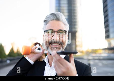 Glücklicher Geschäftsmann im Gespräch auf Smartphone halten Skateboard Stockfoto
