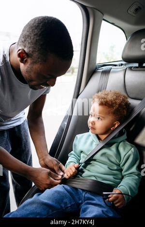 Vater, der den Sicherheitsgurt der im Auto sitzenden Tochter anpasst Stockfoto