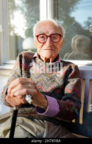 Besorgter älterer Mann mit Gehstock auf der Bank Stockfoto