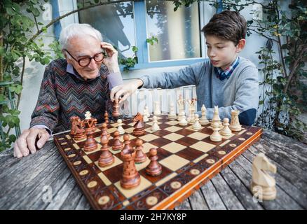Junge spielt Schach mit Großvater im Hinterhof Stockfoto