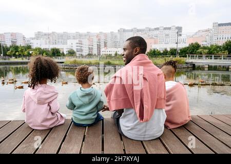 Vater sitzt mit Kindern auf dem Pier in der Stadt Stockfoto
