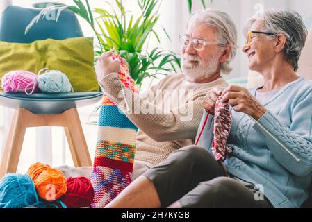 Älterer Mann, der Frau zu Hause Strickwolle zeigt Stockfoto