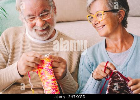 Lächelnde Frau, die zu Hause den Mann, der Wolle strickt, ansieht Stockfoto