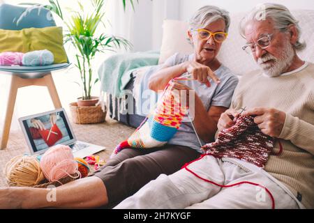 Frau, die dem Mann beibringt, zu Hause Wolle mit Nadel zu stricken Stockfoto