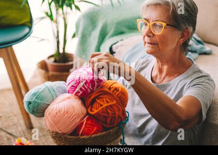 Frau, die zu Hause einen Wollball aus dem Korb wählt Stockfoto