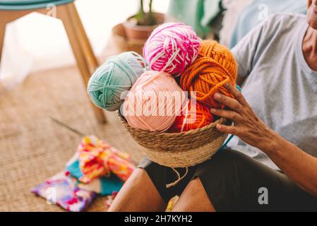 Frau, die einen Korb mit Wollkugeln im Wohnzimmer hält Stockfoto