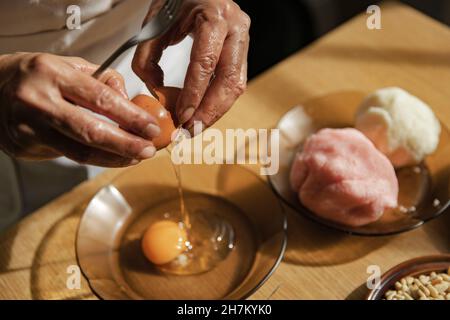 Frau bricht Ei in der Schüssel in der Küche Stockfoto