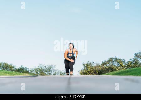 Junge Sportlerin, die auf der Straße läuft Stockfoto