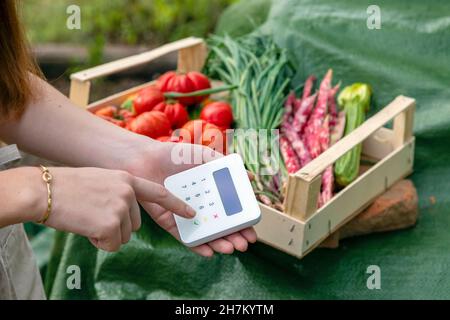 Bäuerin mit Kreditkartenleser im Garten Stockfoto