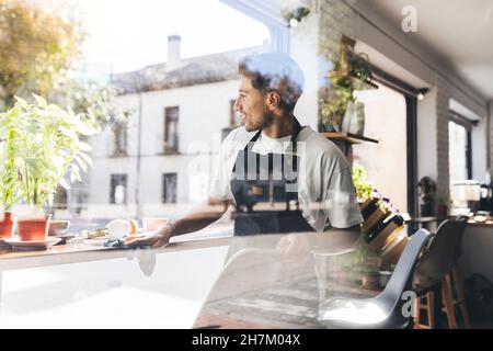 Lächelnder Kellner, der Tisch im Café putzt Stockfoto
