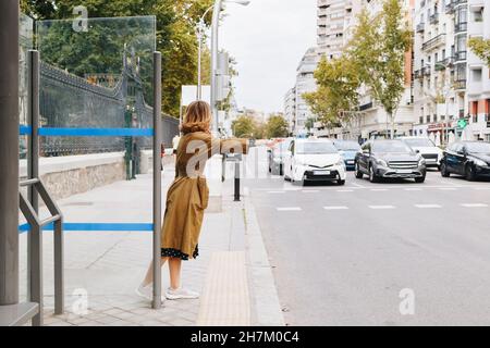 Frau, die ein Taxi auf einem Fußweg in der Stadt anhagelt Stockfoto