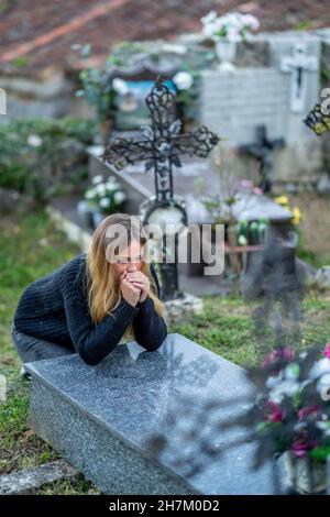 Frau mit Händen umklammert und betet auf dem Friedhof Stockfoto