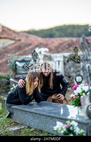 Mann tröstende Frau auf Grabstein auf dem Friedhof Stockfoto