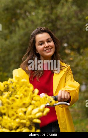 Lächelnde Frau mit Blumen auf dem Fahrrad Stockfoto