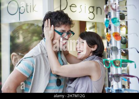 Glückliche Frau versucht Brillen auf Freund im Geschäft Stockfoto