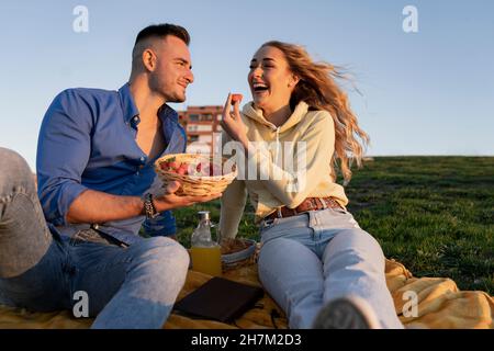 Pärchen genießen Picknick auf dem Hügel bei Sonnenuntergang Stockfoto